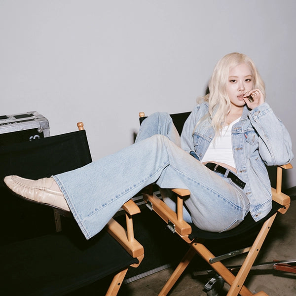 "ROSÉ from BLACKPINK (also known as Rosie) lounging in a director's
chair, wearing a light wash Levi's denim trucker jacket and flared jeans in the
Behind Every Original campaign"
